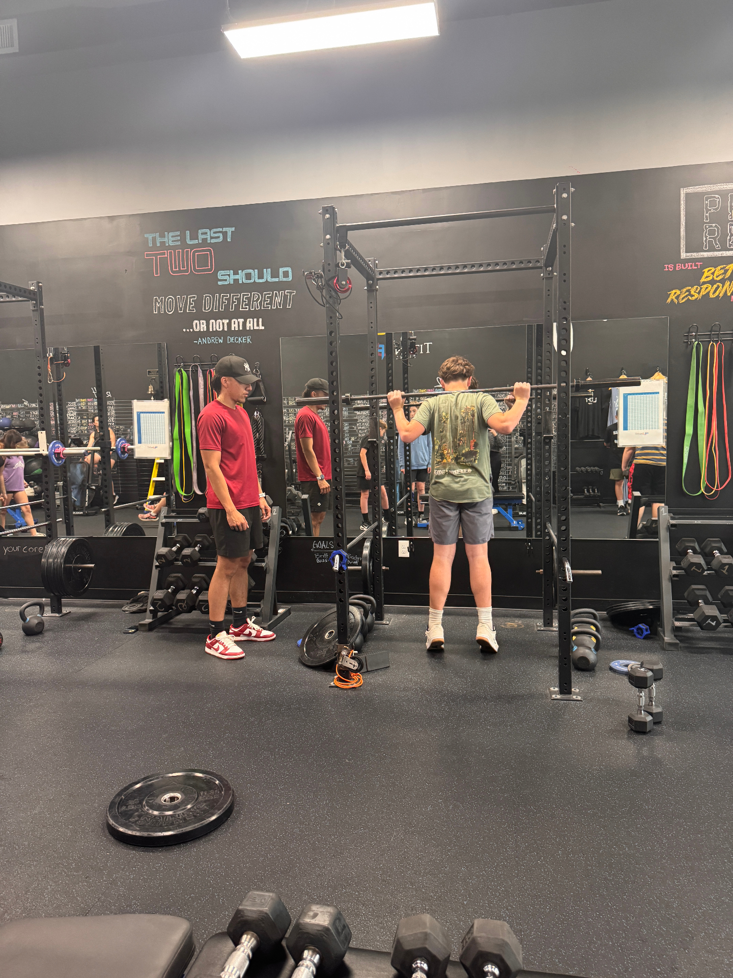 Coach spotting a youth athlete during a barbell back squat
