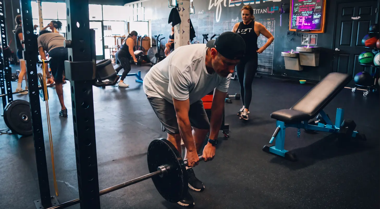 Coach and members setting up barbell work during a group session