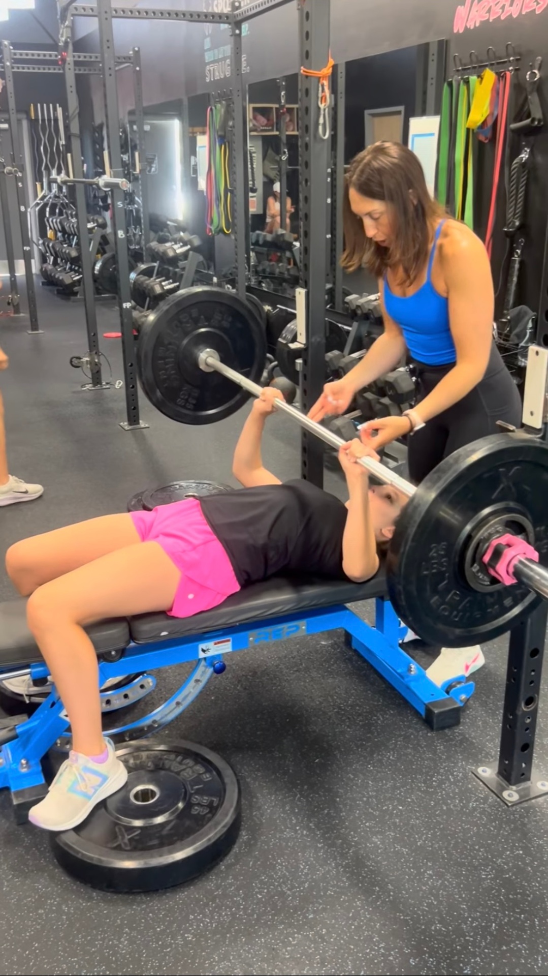 Young athlete bench pressing with coach spotting at TitanUp Nocatee