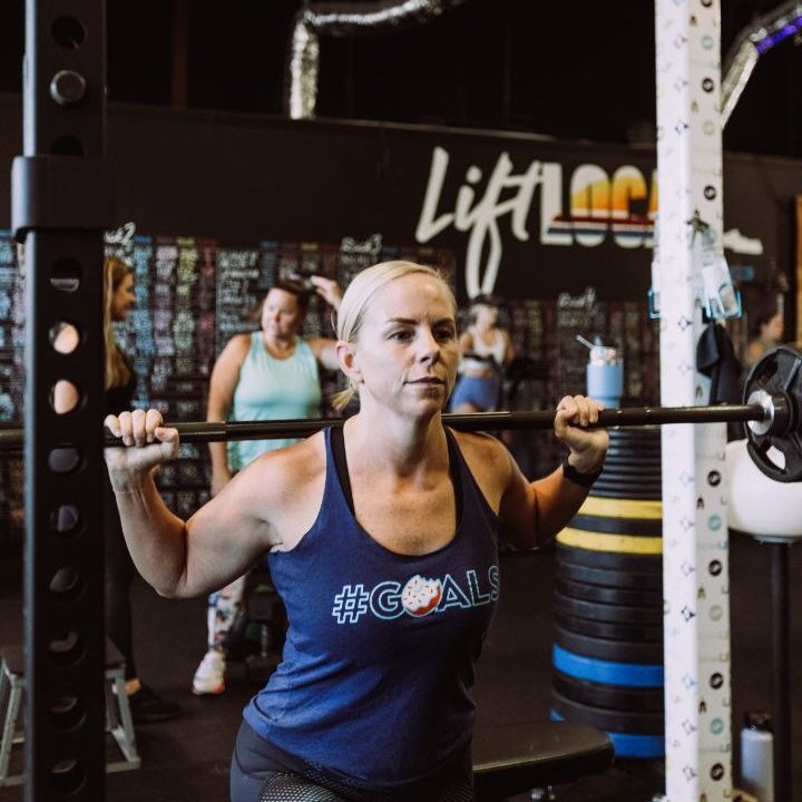 TitanUp member setting up under the barbell in front of the Lift Local wall