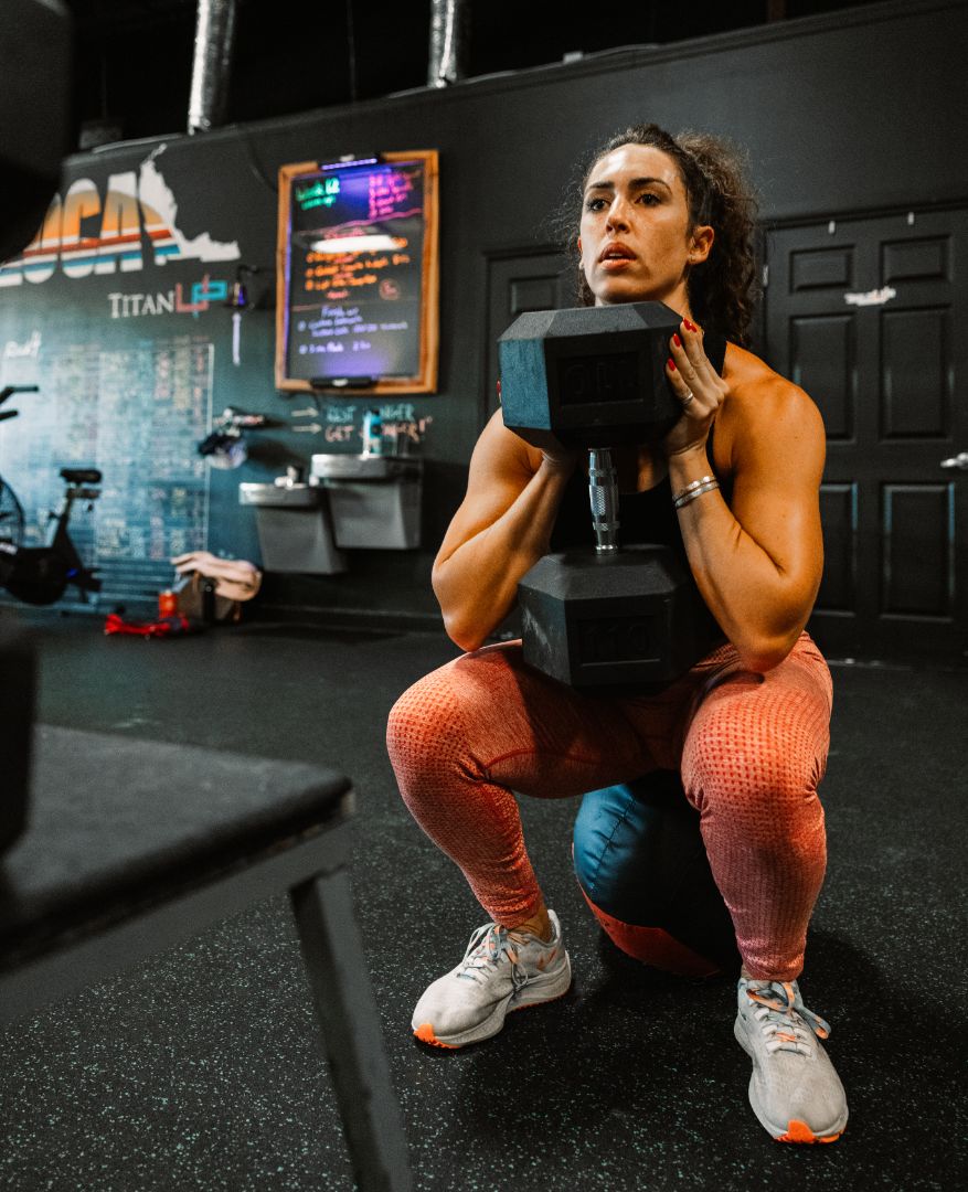 TitanUp member holding a heavy dumbbell in the bottom of a squat