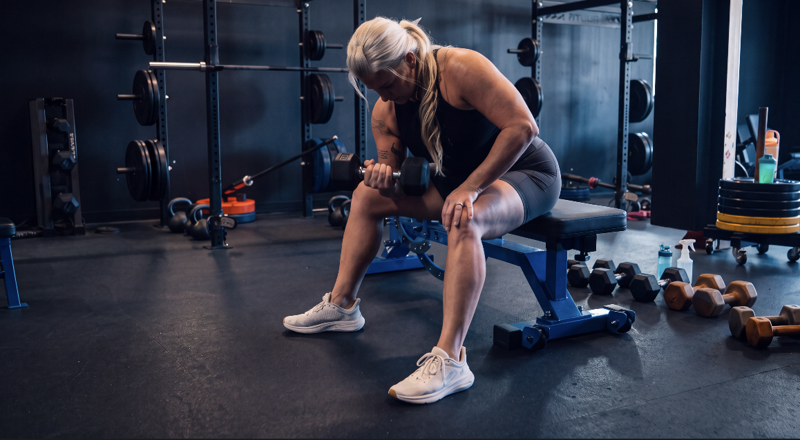 TitanUp member performing a seated dumbbell curl on a bench