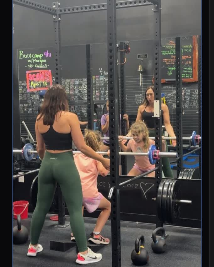Coach guiding young athletes through a barbell squat