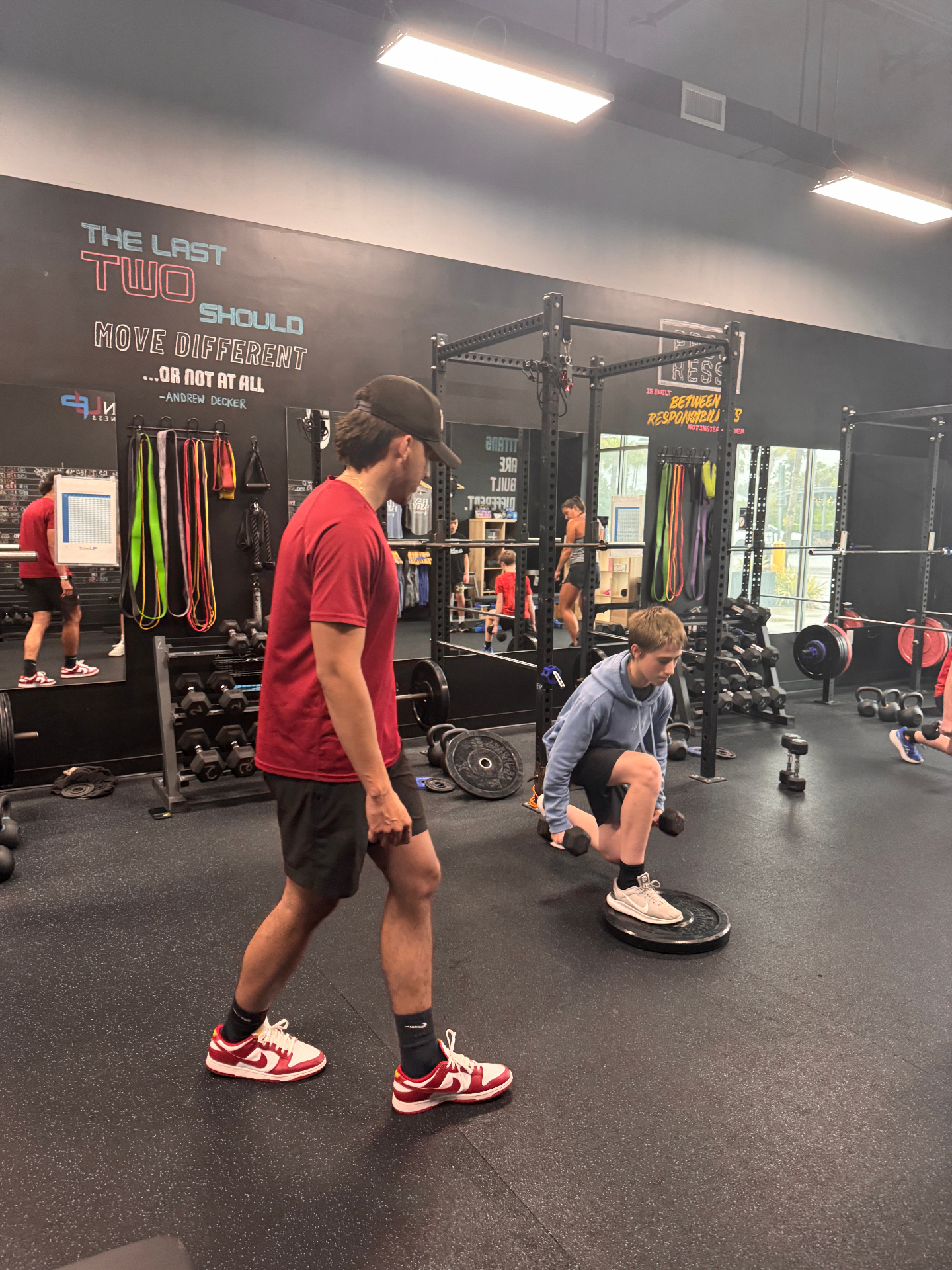 Youth athlete doing a single-leg dumbbell exercise with coach oversight