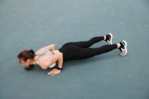 woman in black tank top doing push ups on a grey concrete floor