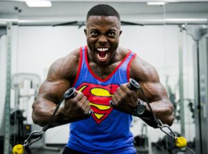 man wearing superman t shirt lifting heavy weights at gym with intense face